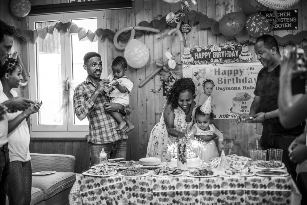 Photo of an asylum seeker family celebrating the first birthday of two of their babies in their new country, Switzerland