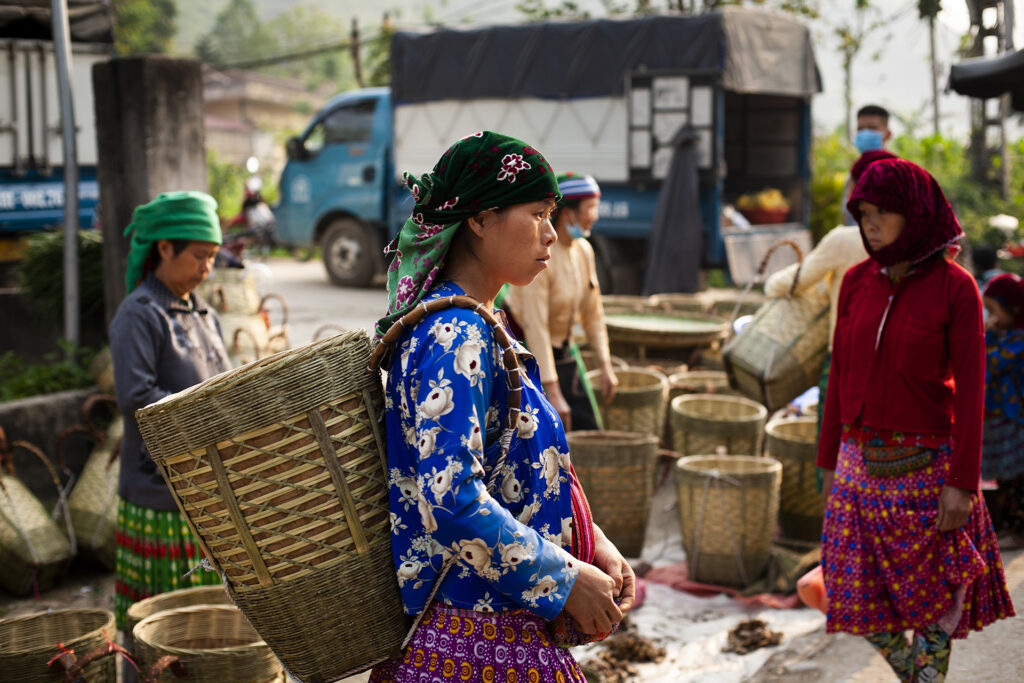 Picture of A Hmong woman at a market, selling traditional woven baskets