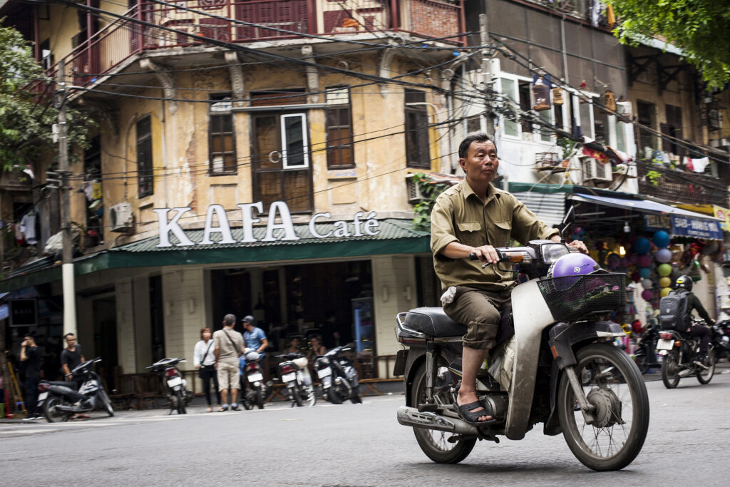 Picture of Vietnamese man on Honda bike with Kafa cafe in background. Vietnam travel photography print
