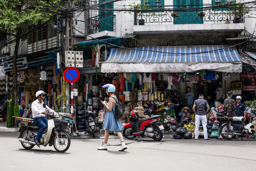 Vietnamese art street scene of a girl in blue outfit walking across the road