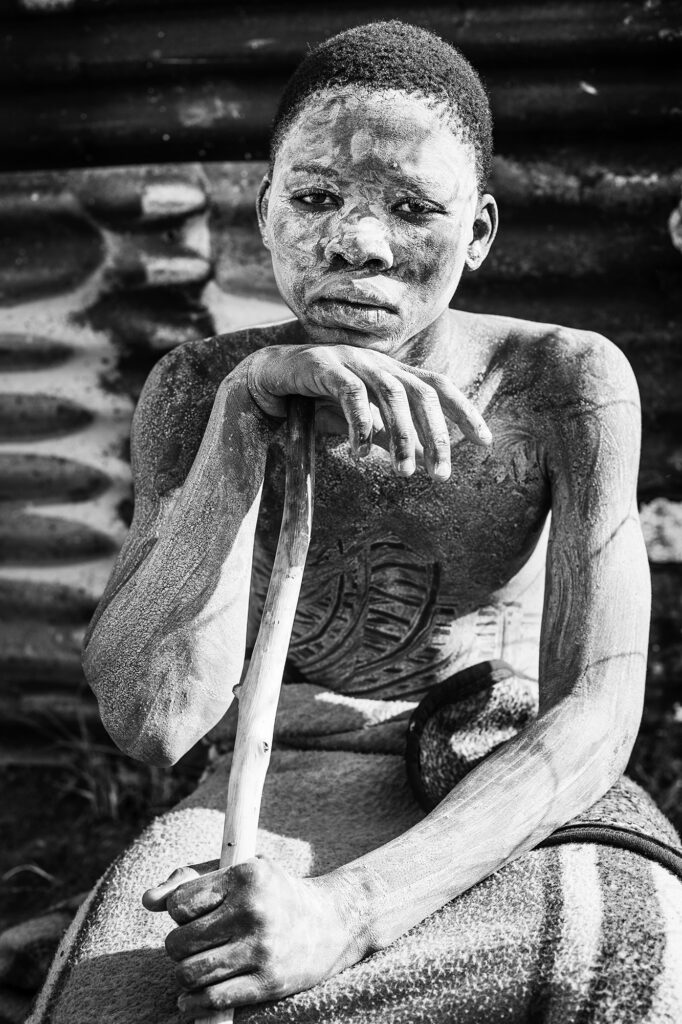 black and white portrait photograph of a young Xhosa man painted in white during the amaXhosa initiation process