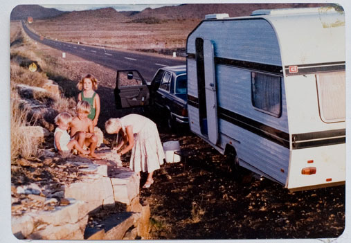 Photo of South African photographer Lavonne Bosman as a child. Picture of three children and their mother next to a caravan on the road.