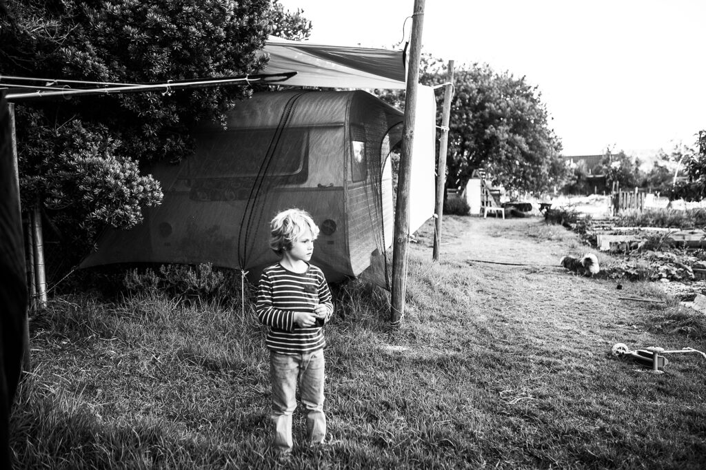 Picture of a young boy standing behind an old caravan